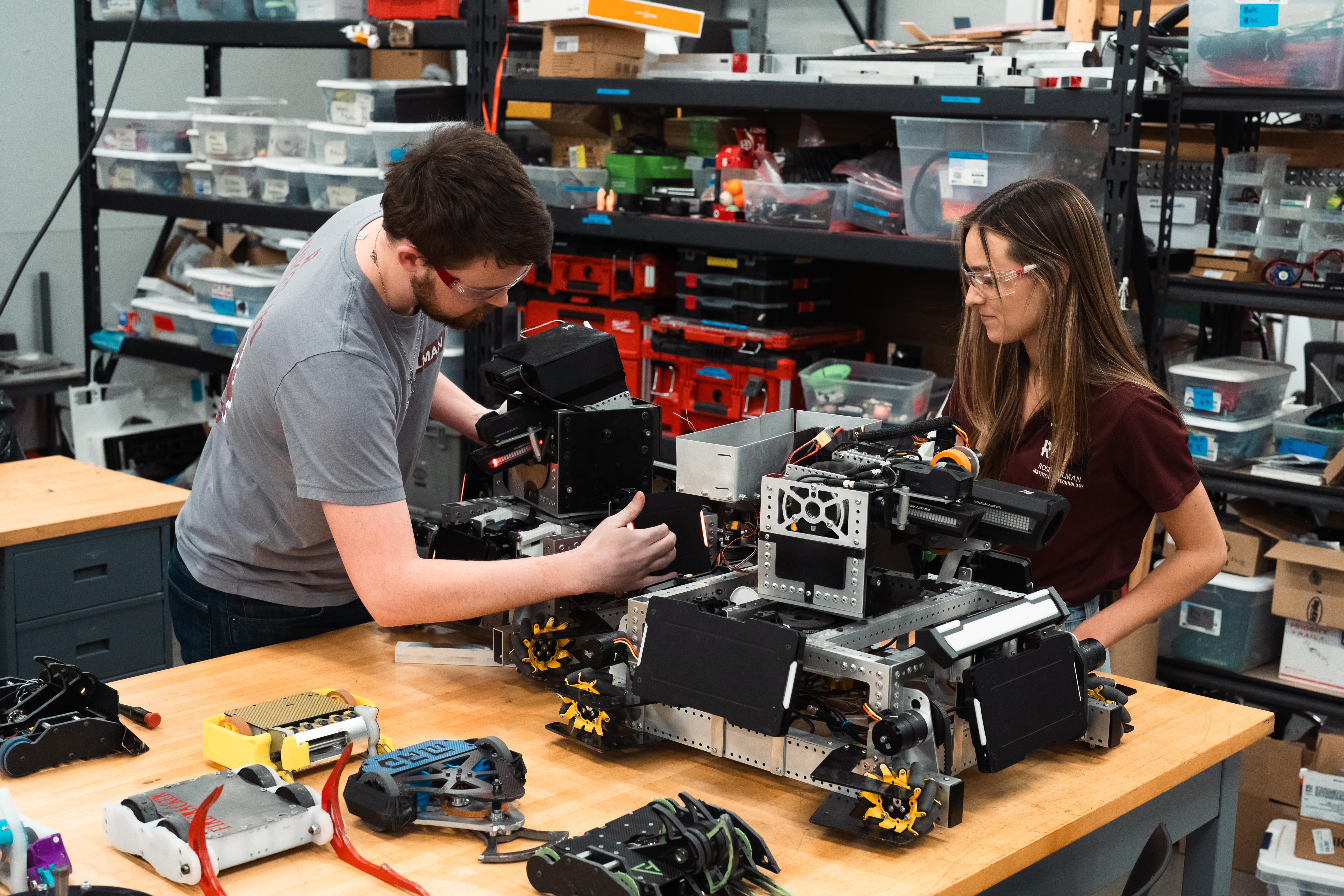 Two students work on a robot on a table in the KIC.